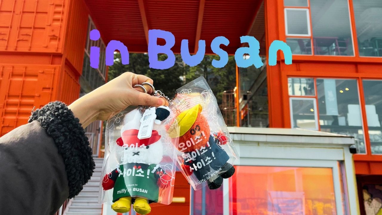 A person holding exclusive Miffy in Busan souvenir keychains in front of the orange store building for travel blog thumbnail.