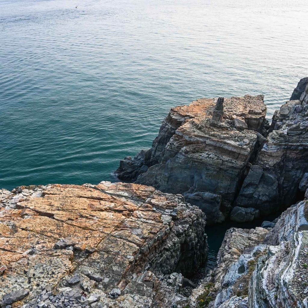Rugged rocky cliffs and rock formations meeting the deep blue ocean at Taejongdae Resort Park in Busan, South Korea.